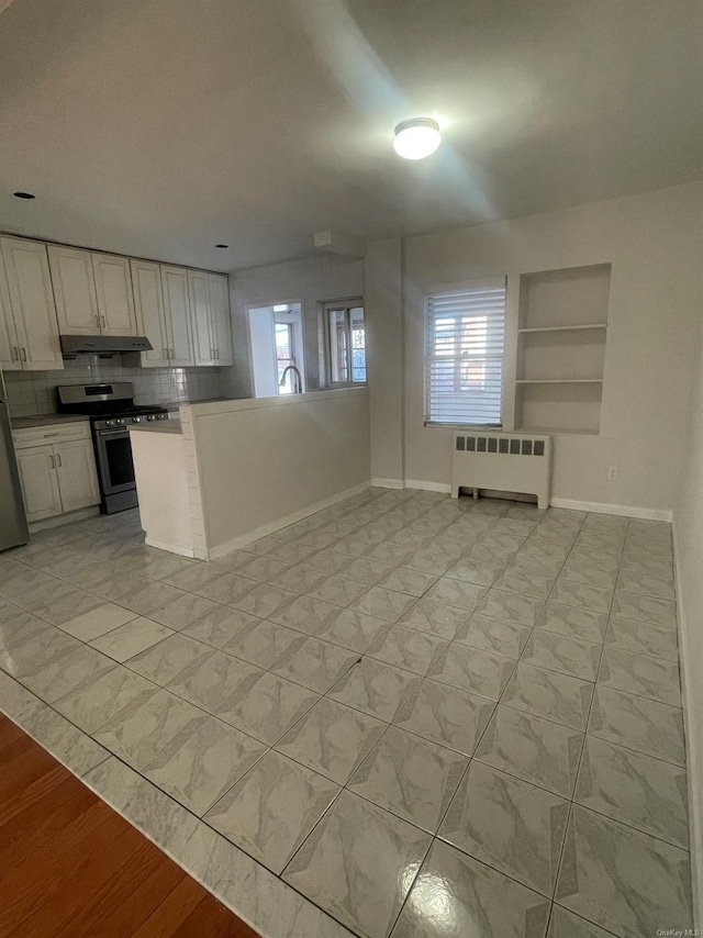 kitchen featuring decorative backsplash, white cabinetry, radiator heating unit, and stainless steel appliances