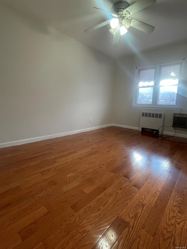 empty room featuring radiator heating unit, hardwood / wood-style flooring, and ceiling fan