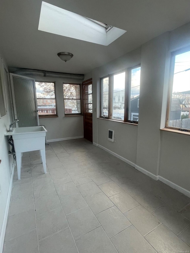 unfurnished sunroom with heating unit and a skylight