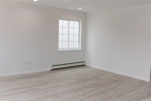 empty room with light wood-type flooring and a baseboard heating unit