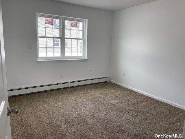 carpeted empty room with baseboard heating