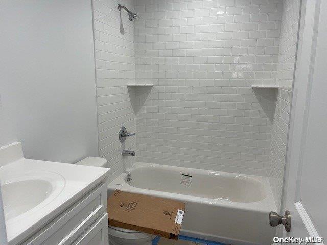 full bathroom featuring vanity, tiled shower / bath, and toilet