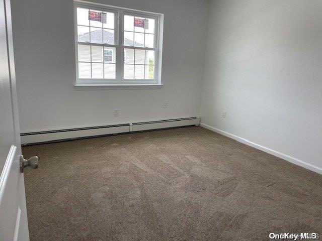 carpeted empty room with a baseboard radiator