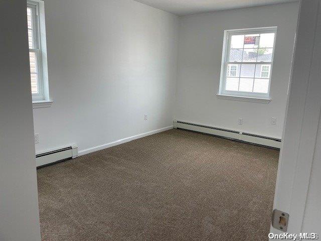 carpeted spare room with a baseboard radiator