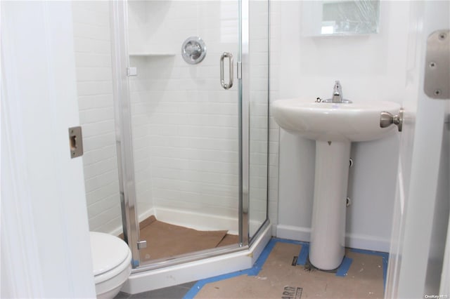 bathroom with toilet, an enclosed shower, and sink