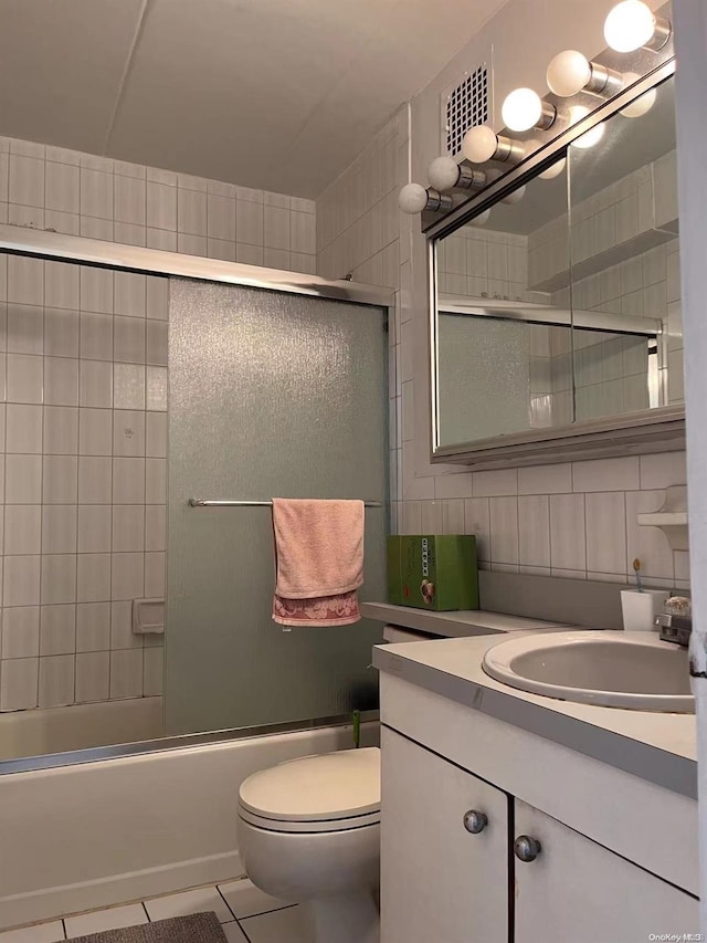 full bathroom with backsplash, tile patterned floors, bath / shower combo with glass door, toilet, and tile walls