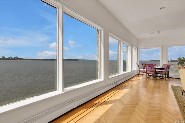 sunroom with baseboard heating and a water view