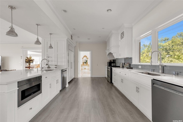 kitchen with appliances with stainless steel finishes, sink, white cabinetry, and pendant lighting