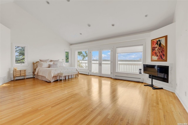 bedroom featuring a baseboard heating unit, light wood-type flooring, access to exterior, french doors, and vaulted ceiling