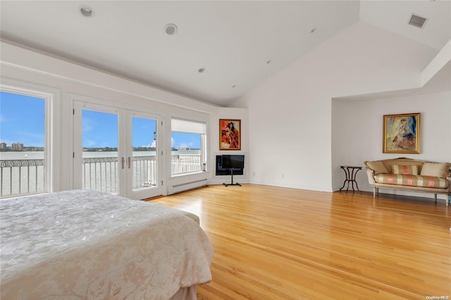 bedroom featuring a baseboard radiator, light wood-type flooring, french doors, access to exterior, and vaulted ceiling