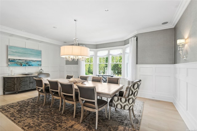 dining space with an inviting chandelier, crown molding, and light hardwood / wood-style flooring