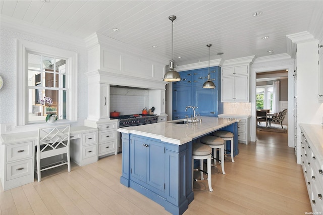 kitchen with sink, decorative light fixtures, a kitchen island with sink, high end stainless steel range, and white cabinets