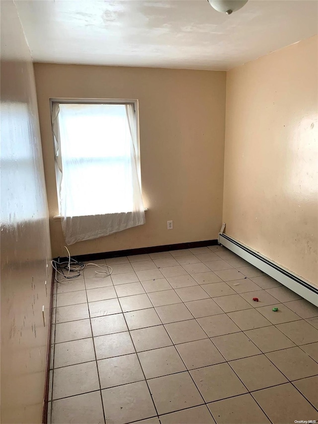 spare room featuring a baseboard heating unit and light tile patterned flooring