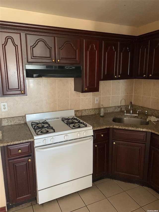 kitchen featuring white gas stove, light tile patterned flooring, sink, and tasteful backsplash