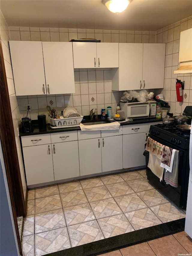 kitchen featuring white cabinetry, black range with gas cooktop, tasteful backsplash, and sink