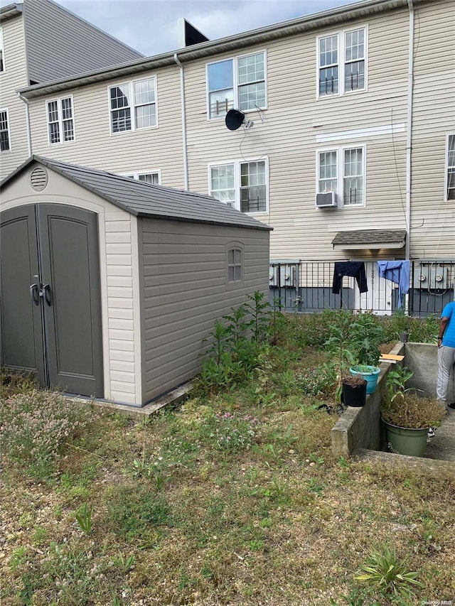 back of property featuring cooling unit and a shed