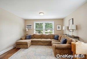 living room with wood-type flooring and a wall unit AC