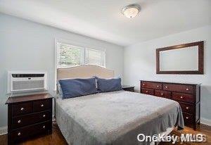 bedroom with a wall unit AC and dark wood-type flooring