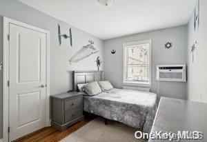 bedroom featuring a wall mounted AC and dark hardwood / wood-style flooring