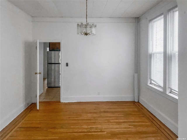 unfurnished room with a chandelier and hardwood / wood-style floors