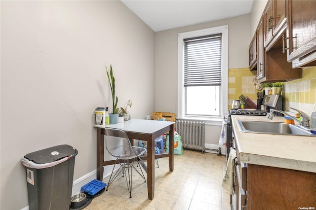 kitchen with decorative backsplash, radiator heating unit, gas stove, and sink