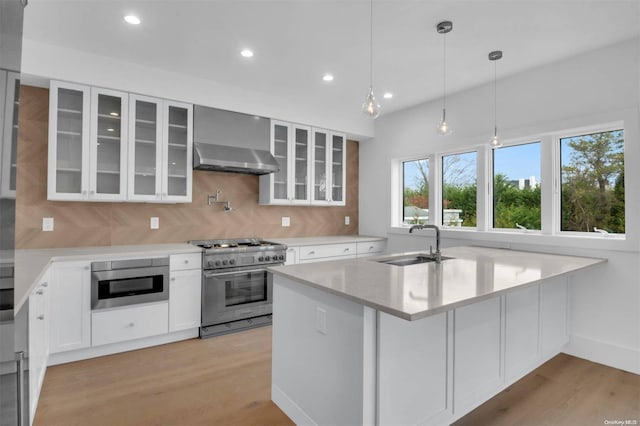 kitchen with pendant lighting, sink, light hardwood / wood-style flooring, white cabinetry, and stainless steel appliances