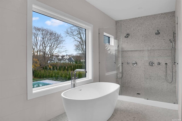 bathroom featuring tile walls and plus walk in shower