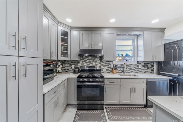 kitchen featuring light stone countertops, decorative backsplash, stainless steel appliances, sink, and gray cabinets