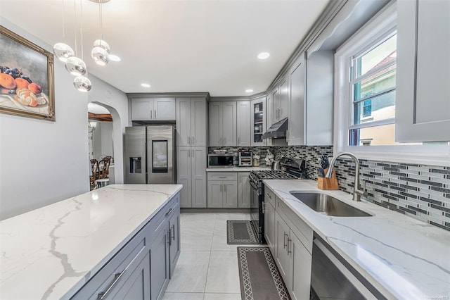 kitchen featuring light stone countertops, sink, hanging light fixtures, and appliances with stainless steel finishes