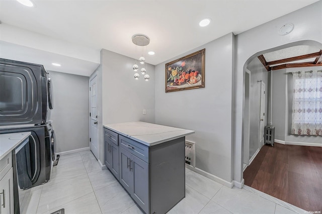 washroom with radiator heating unit, light wood-type flooring, and stacked washer and dryer