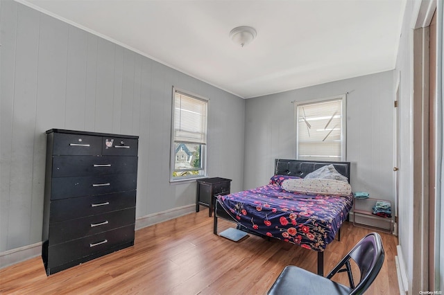 bedroom featuring ornamental molding, multiple windows, and light hardwood / wood-style flooring