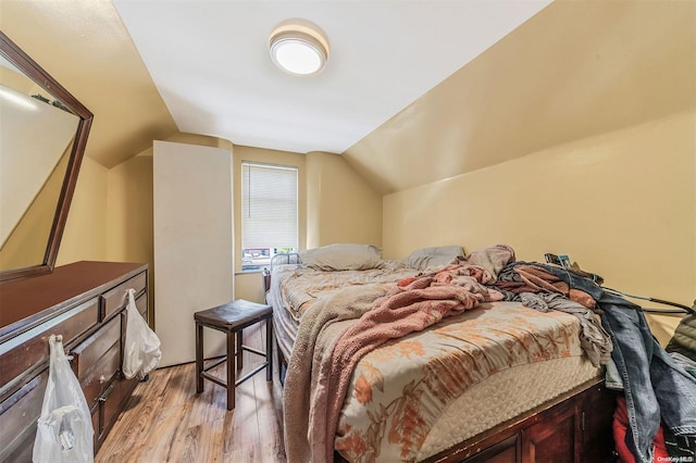 bedroom featuring light wood-type flooring and vaulted ceiling