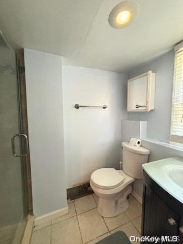 bathroom with tile patterned flooring, vanity, toilet, and walk in shower