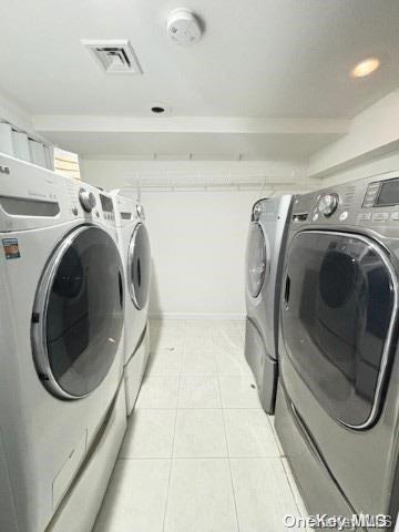 clothes washing area with washer and clothes dryer and light tile patterned floors