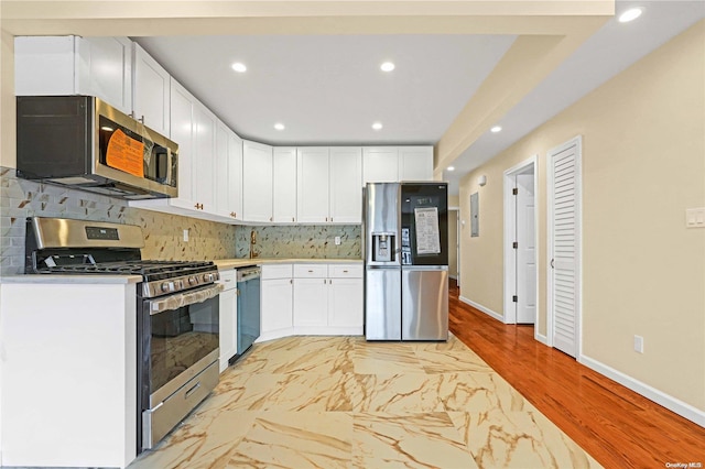 kitchen with white cabinets, light hardwood / wood-style floors, backsplash, and appliances with stainless steel finishes