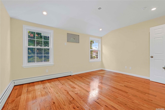 unfurnished room with light hardwood / wood-style flooring, vaulted ceiling, and a baseboard heating unit