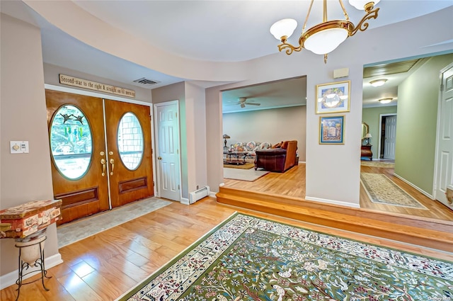 entrance foyer with french doors, ceiling fan with notable chandelier, light hardwood / wood-style floors, and a baseboard heating unit