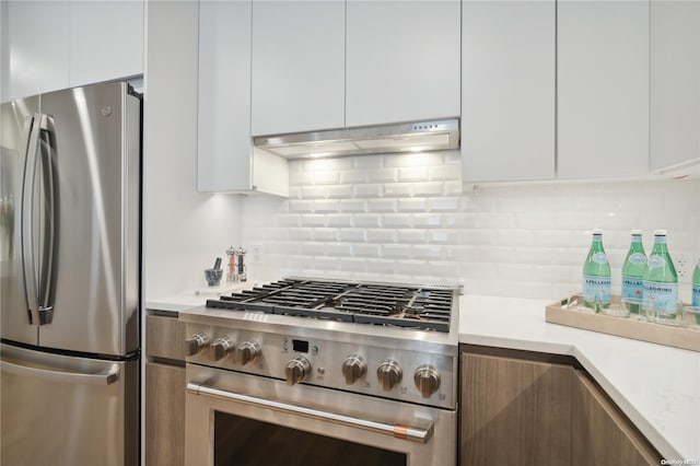 kitchen featuring white cabinets, appliances with stainless steel finishes, decorative backsplash, and range hood