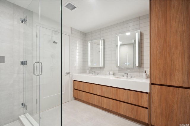 bathroom with vanity, a shower with shower door, tile walls, and tasteful backsplash