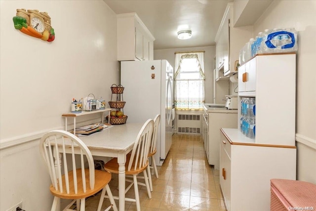 kitchen featuring white cabinets, white refrigerator, light tile patterned flooring, and radiator heating unit