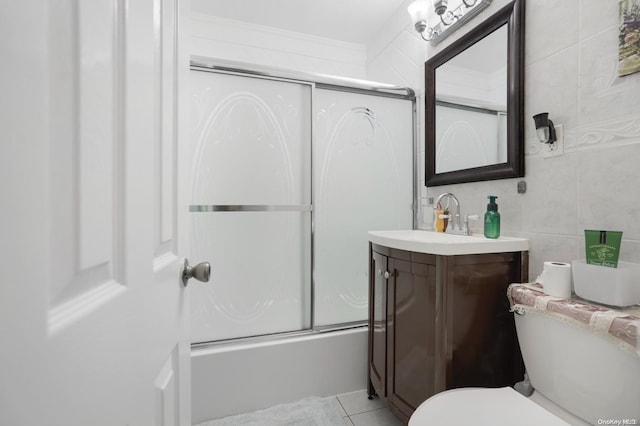 full bathroom featuring combined bath / shower with glass door, toilet, vanity, tile walls, and ornamental molding