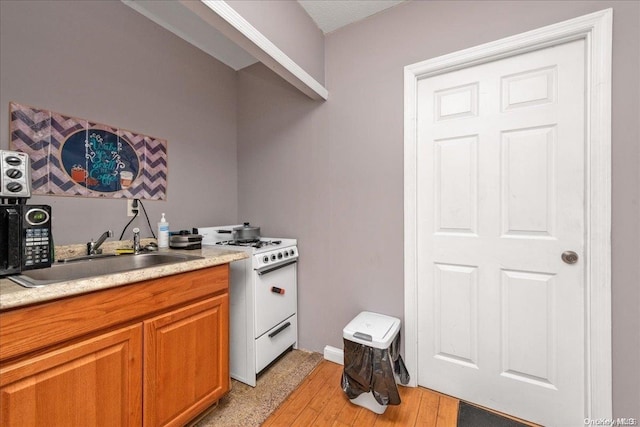 kitchen with light hardwood / wood-style flooring, white range, and sink