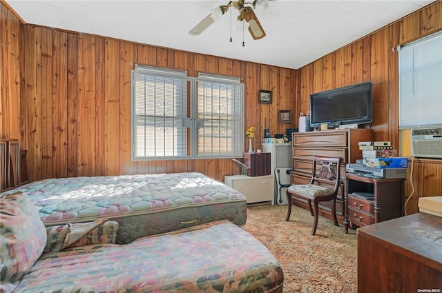 bedroom with ceiling fan, wooden walls, and light carpet