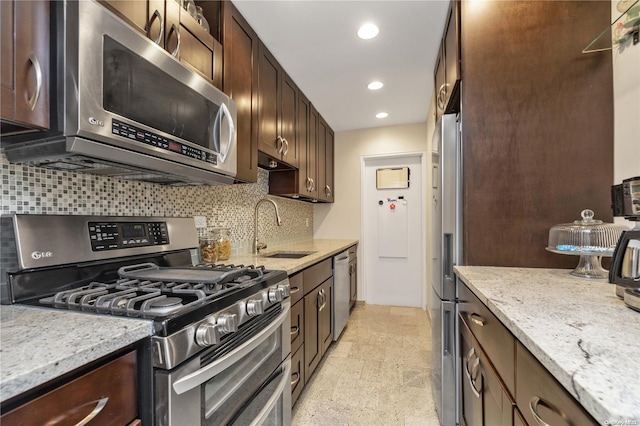 kitchen featuring light stone countertops, dark brown cabinetry, stainless steel appliances, and sink