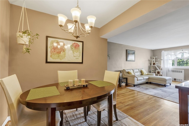 dining room featuring radiator heating unit, a notable chandelier, and hardwood / wood-style flooring