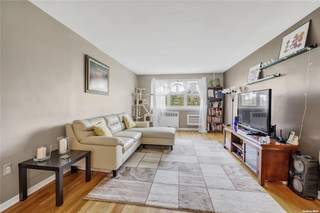 living room featuring a wall mounted air conditioner, light hardwood / wood-style floors, and radiator