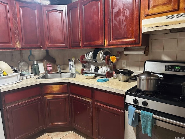 kitchen with backsplash, light tile patterned floors, sink, and stainless steel range