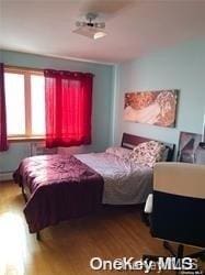 bedroom with hardwood / wood-style flooring and baseboard heating