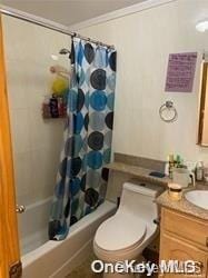 full bathroom with vanity, toilet, ornamental molding, and shower / tub combo with curtain