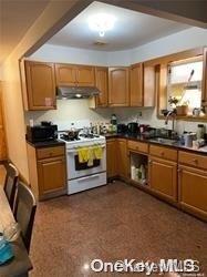 84-38 Grand Ave, Elmhurst, NY 11373 - kitchen featuring extractor fan, white gas stove, dark countertops, and brown cabinets